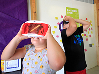 Two children using virtual reality goggles.