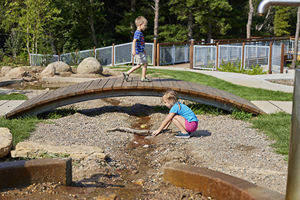 Two kids playing at Fawn Crossing Nature Play Area.