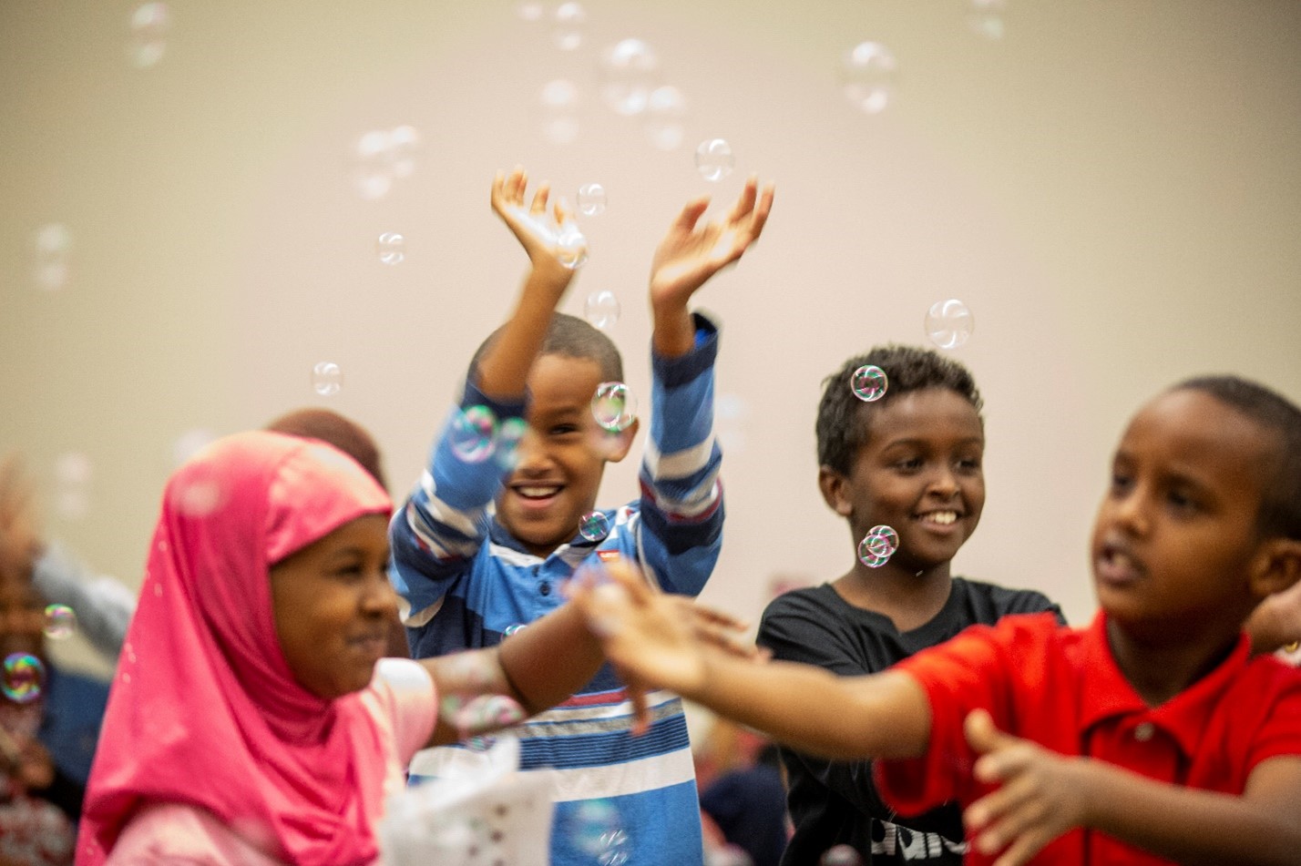 Somali children playing with bubbles at a library event.