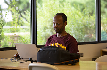 Man sitting at a desk, looking at his laptop.