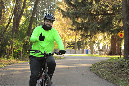 Man in cold weather gear riding the trail on a bicycle.