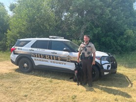 Domenic Scudera and Vader in front of a squad car.