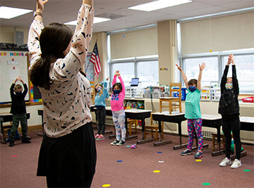 Teacher and students with hands outstretched. 