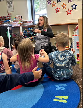 Teacher sitting on the floor in front of her preschool class.