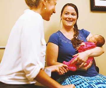 Mother holding her baby with a WIC nurse.