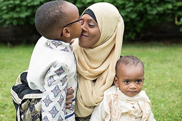 Woman holding two young children.