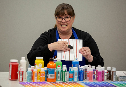 Painting instructor with bottles of paint in front of her. 