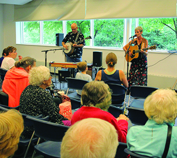 Two performers playing a banjo and guitar at the library.