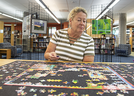 Woman putting together a puzzle at a library location.