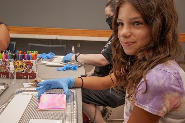 Girl holding a ceramic tiles at an arts and crafts event.