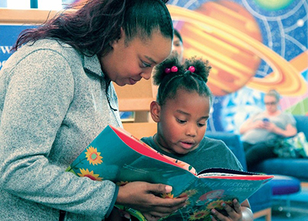 A woman reading a children's book to her child.