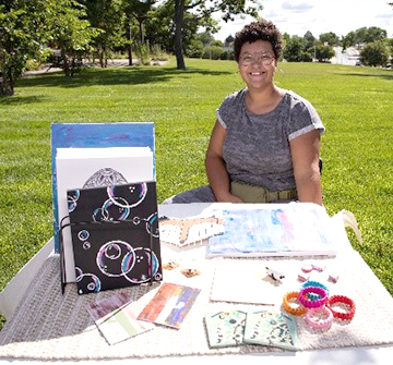 Youth girl sitting a table with her crafts at a craft fair.
