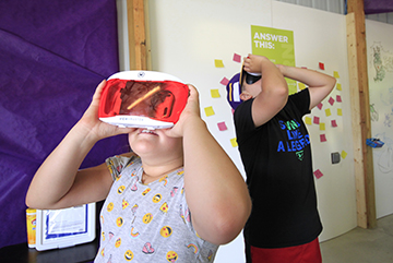 Two children wearing virtual reality goggles.