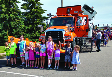 Kids standing in front of a Dakota County snowplow.