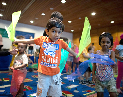 Children waving scarves at a library program.