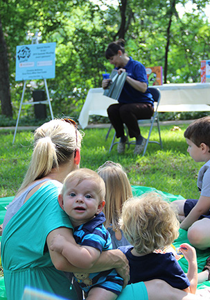 Mother holding a baby at an outdoor storytime.