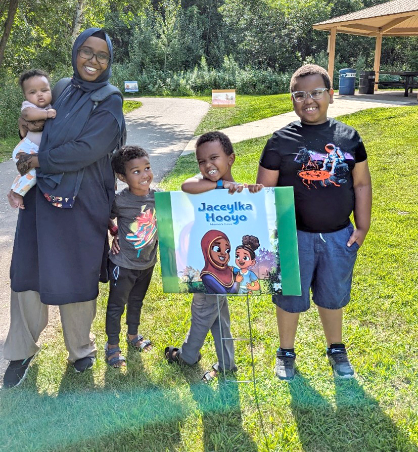 Five Somali children posing with a book page on a Story Trail.