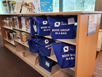 Shelf filled with Book Group Kit baga.