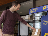 Man picking up bags of materials from shelf outside the library.