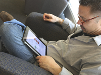 Man with tablet on his lap, reading an e-book.