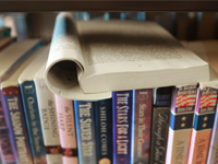 An open book on a library bookshelf.