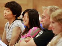 Three people listening intently at a library event.