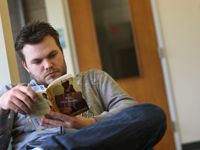 Man sitting in a chair, reading a book.