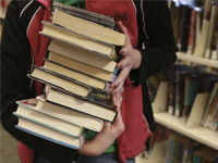 Closeup of a person holding a stack of books.
