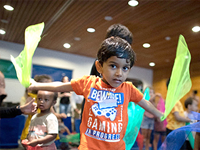 Child waving pieces of fabric at a Noon Year's Eve Party.