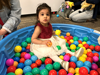 Girl sitting in a pool with colorful, plastic balls.