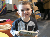 Child holding a book and smiling.