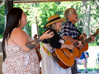 Three people singing at an outdoor library music event.