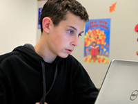 Boy looking at a computer monitor. 