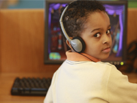 Child at a computer with headphones.