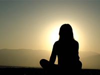 Silhouette of person meditating during a sunset.
