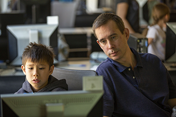 Boy and man looking at a computer screen.