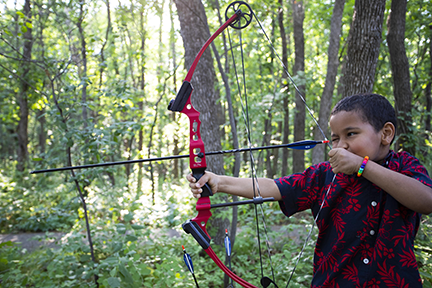 Boy aiming a bow at a target.