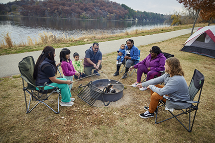 Family roasting marshmellows around a bonfire.