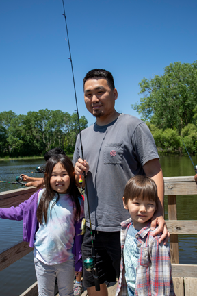 Dad with two kids on fishing pier.