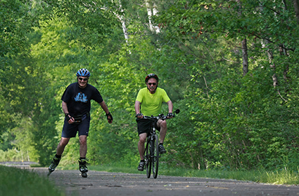 Biker and inline skater traveling side-by-side down a trail.