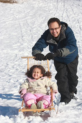 Man pushing a child ina  kicksled.