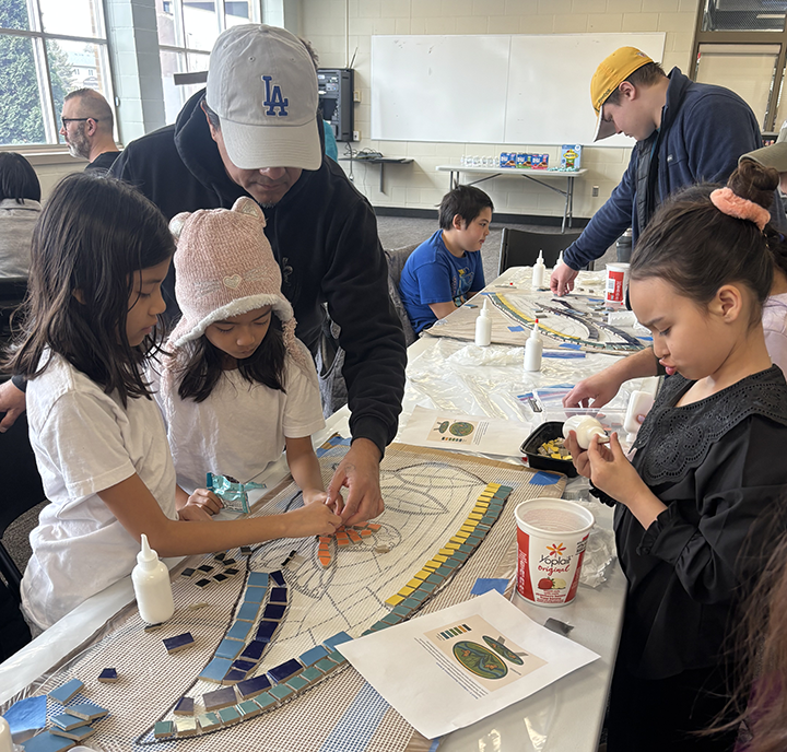 Family completing a hand-on mosaic art activity.