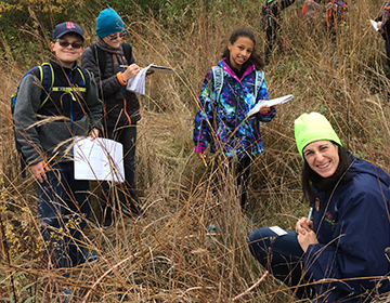 Three kids and an instructor smiling in a prairie.