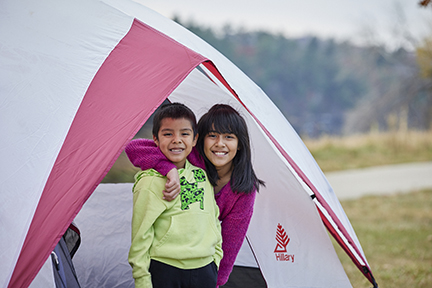 Two children standing at the entrance of a tent.