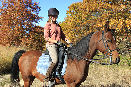 Woman horseback riding in the fall.