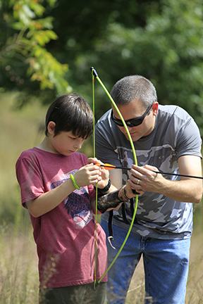 Father showing his son how to shoot an arrow.