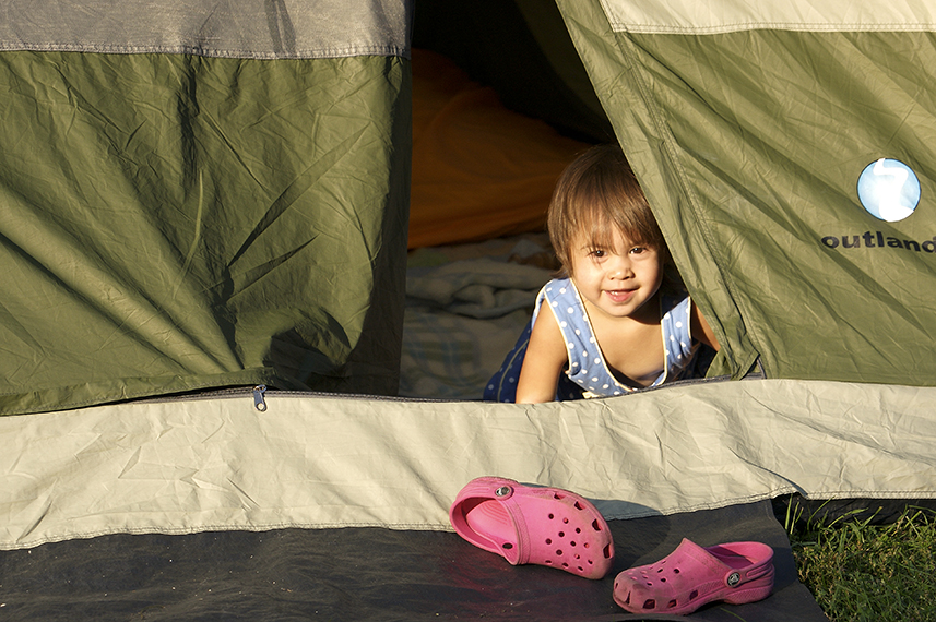 Smiling toddler looking out a tent.