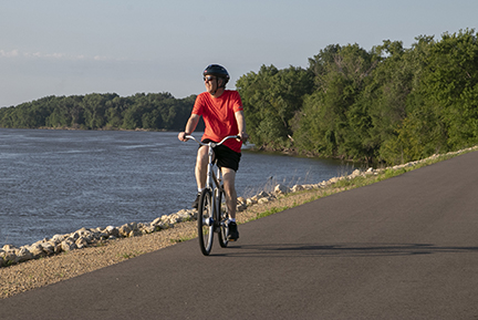 Man riding a bike on a paved trail.