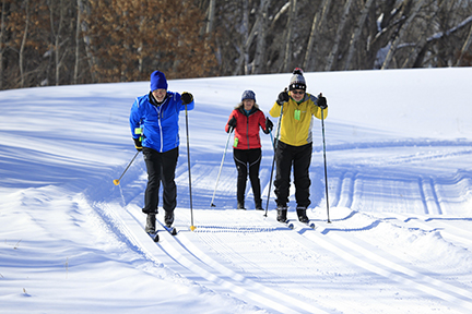 Three cross-country skiiers on a groomed trail.