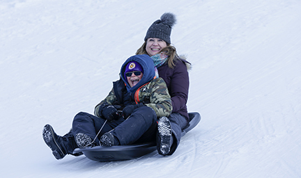 Mother and son riding a toboggan down the sledding hill.